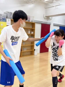 トレーナーの指導を受けながらディフェンス練習をする会員