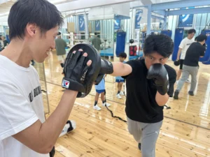 トレーナーとパンチのフォームを確認しながら練習する会員