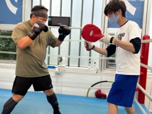 リング上でトレーナーのミットにパンチを打つ会員