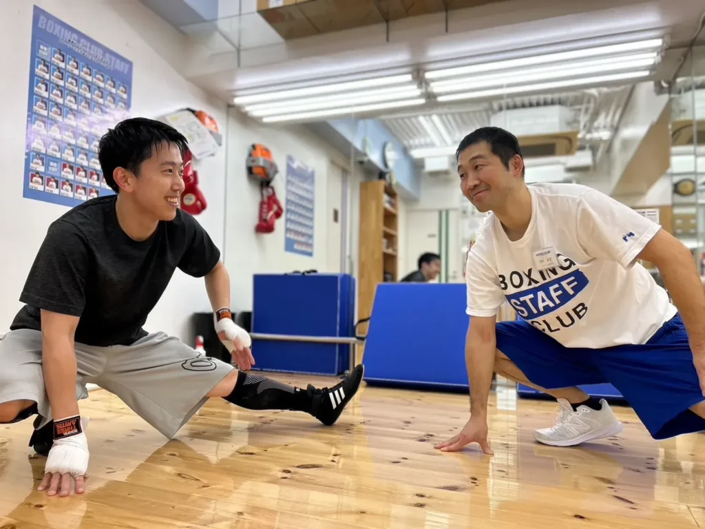 会員と一緒にストレッチを行うボクシングトレーナー